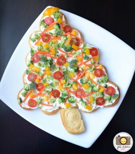This is made from either bread or pizza dough spread over with cream cheese as well as topped with carrots, cherry tomatoes, yellow peppers, and broccoli. Still, it's a healthier option than the cheese candle wreath one. Yet, won't satisfy vegans.