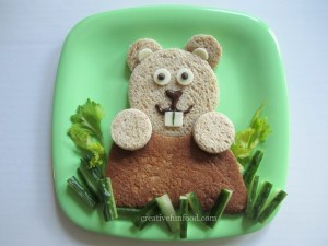Okay, now the ground is made from a whole wheat tortilla while the groundhog is made from bread. The grass is of lettuce and cucumber. And the white stuff of cheese. Yet, I'm sure your child will love it since it's so cute.