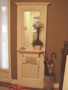 This includes a shelf, mirror, and mail bin. The flowers add a decorative touch.