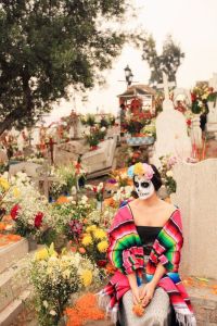 Well, at least she's in a cemetery, perhaps to honor her dead relatives. Yet, I do like her multicolored serape.