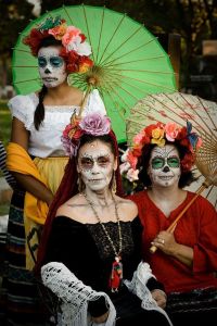 Here we have 3 generations of a family in their skull face makeup and flowers. Two of them carry parasols in hand.