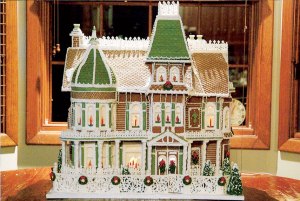 This one has wreath decorations on the fence and candles in the window. Love the lattice work on the roof.